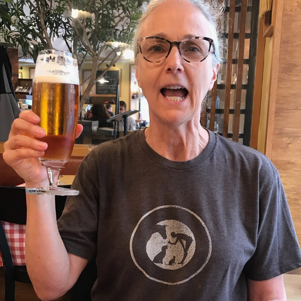 Women with a beer in her hand wearing a Macchiato colored 100% Cotton T shirt with Sit.Stay.Forever. logo in the center.