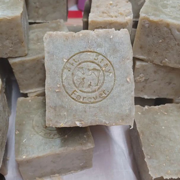 A stack of Sit.Stay.Forever Neem & Hemp Sheath and Udder Cleaner soap bars with the logo embossed on each bar.