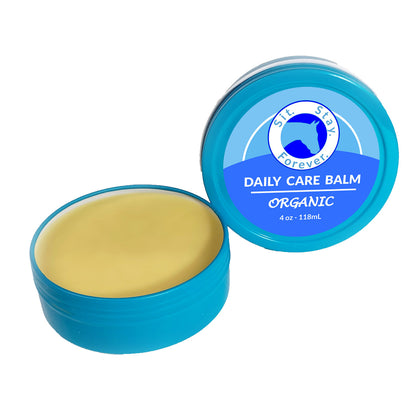 Two blue containers of Sit. Stay. Forever. DAILY CARE BALM ORGANIC 4 oz - 118 mL are shown. One container is open, revealing the balm inside, while the other is closed, displaying the label with the product logo and information.