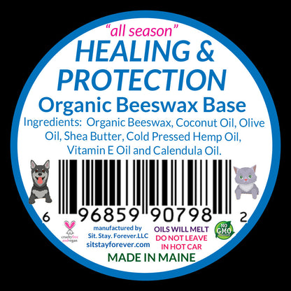 The back label of the "Sit.Stay.Forever. paw salve" tin showing the ingredients list and product details. The label includes the text "HEALING & PROTECTION," and lists ingredients like Organic Beeswax, Coconut Oil, Olive Oil, and more. It also includes a barcode and small illustrations of a dog and a cat.