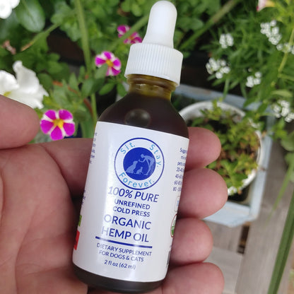 Hand holding a 2 fl oz (62 ml) of 100% Pure Unrefined Cold Press Organic Hemp Oil. The label has the Sit.Stay.Forever. logo and indicates that this product is a dietary supplement for dogs and cats. The bottle has a white dropper cap for easy dispensing.