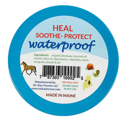 A close-up of the label for "Sit. Stay. Forever." Daily Care Balm. The label reads "HEAL SOOTHE PROTECT waterproof" and lists the ingredients: organic beeswax, coconut oil, lanolin, olive oil, shea butter, calendula, neem, hemp oil, vitamin E oil. It also includes a barcode, manufacturing information, and storage instructions. The product is manufactured by Sit. Stay. Forever. LLC in Maine. The label advises that oils will melt and to not leave the product in a hot car.