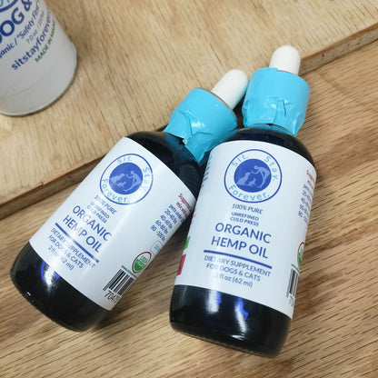 Two 2 fl oz (62 ml) of 100% Pure Unrefined Cold Press Organic Hemp Oil bottles. The label has the Sit.Stay.Forever. logo and indicates that this product is a dietary supplement for dogs and cats. The bottles have a white dropper cap for easy dispensing.
