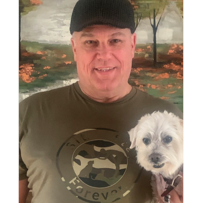 Man wearing an army green colored 100% Cotton T shirt with Sit.Stay.Forever. logo in camouflage style positioned in the center of the shirt. The man is smiling and holding a white dog.