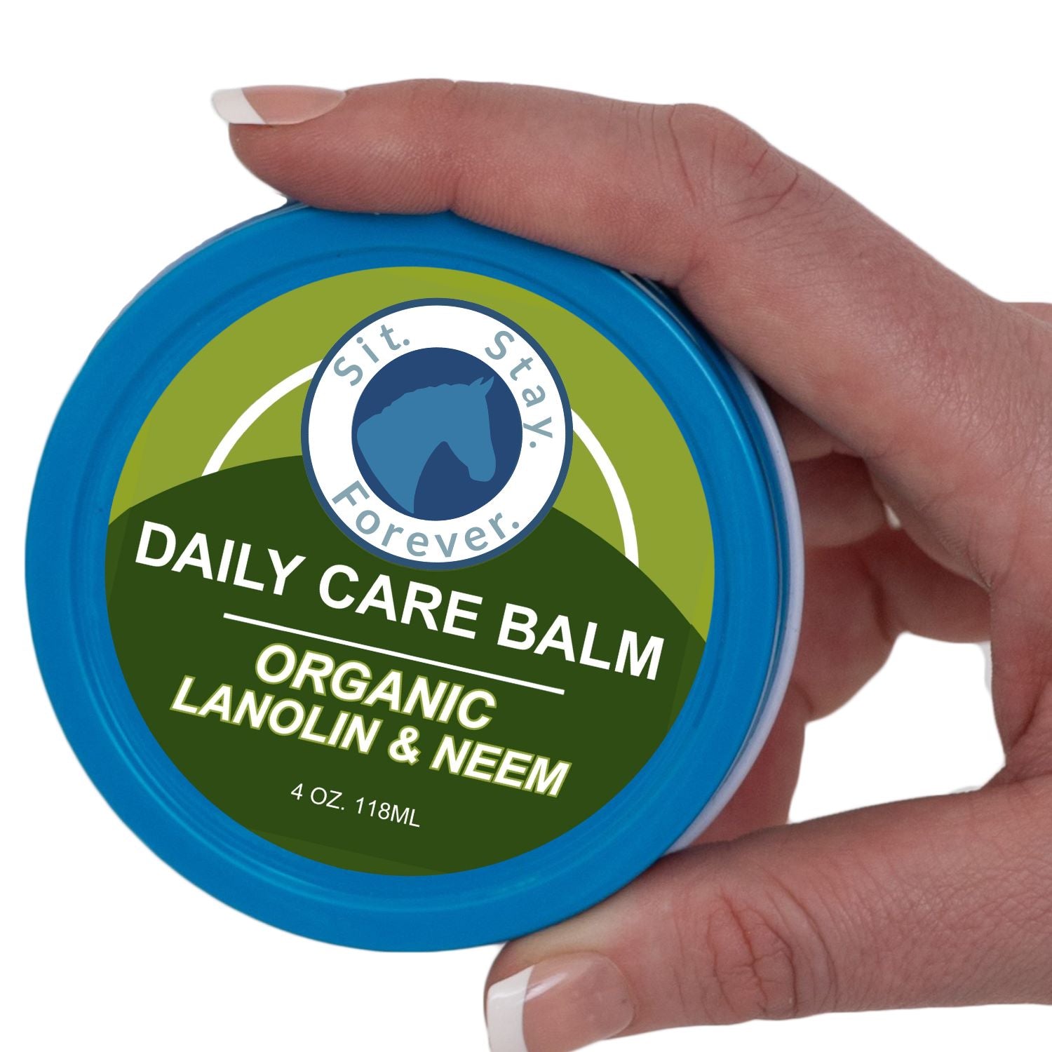 A hand holding a round blue tin of Sit Stay Forever Daily Care Balm Organic Lanolin & Neem against a white background.