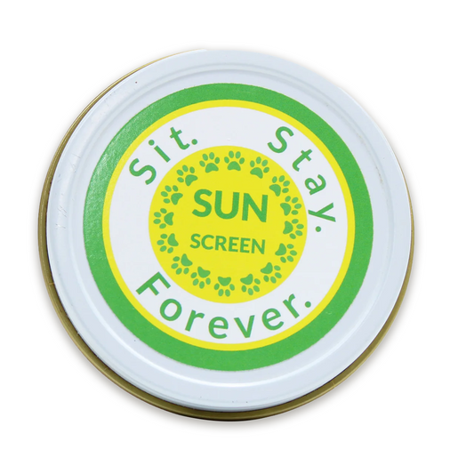 A round tin of sunscreen with a green and yellow label reading Sit.Stay.Forever. SUN SCREEN.